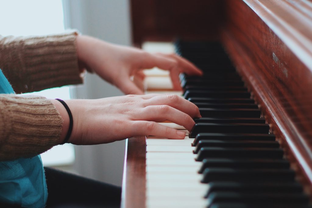 person wearing brown sweater playing piano